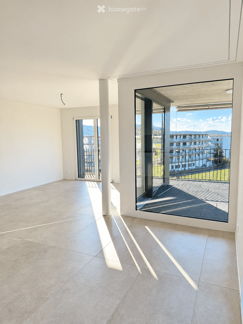 Bright, unfurnished room with large glass doors leading to a balcony, tiled floor, and modern white walls.