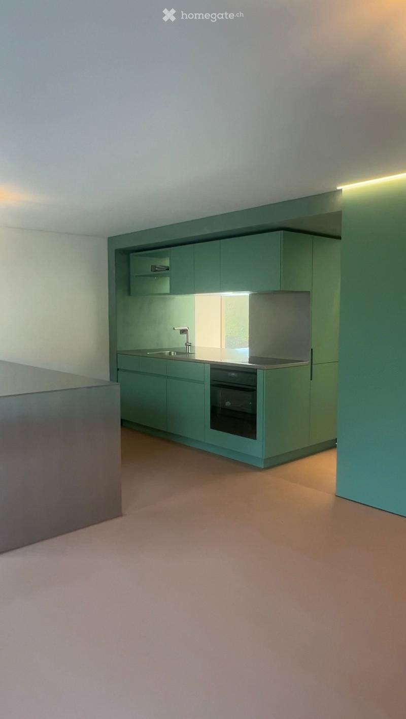 Modern kitchen with green cabinets, a sink, a faucet, and an oven, illuminated by built-in lighting.