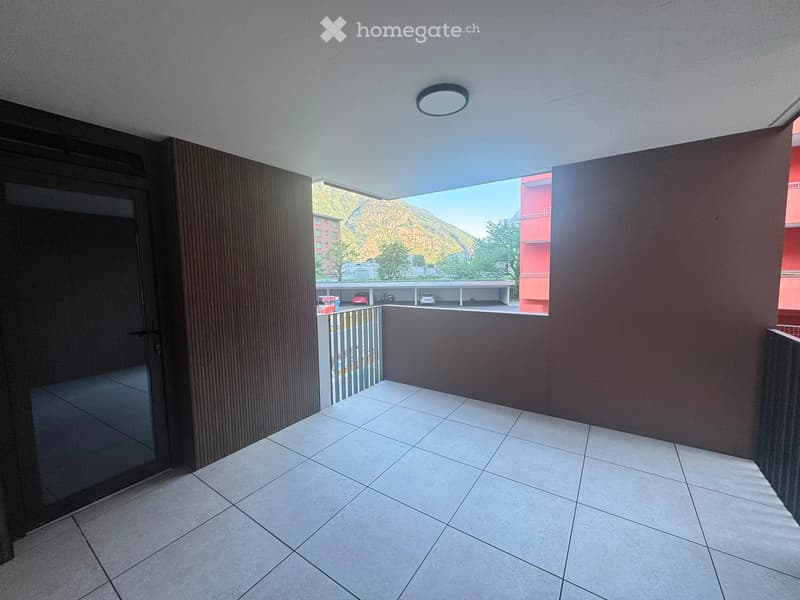 Balcony with tiled floor, modern railing, and a view of a parking area and mountain landscape.
