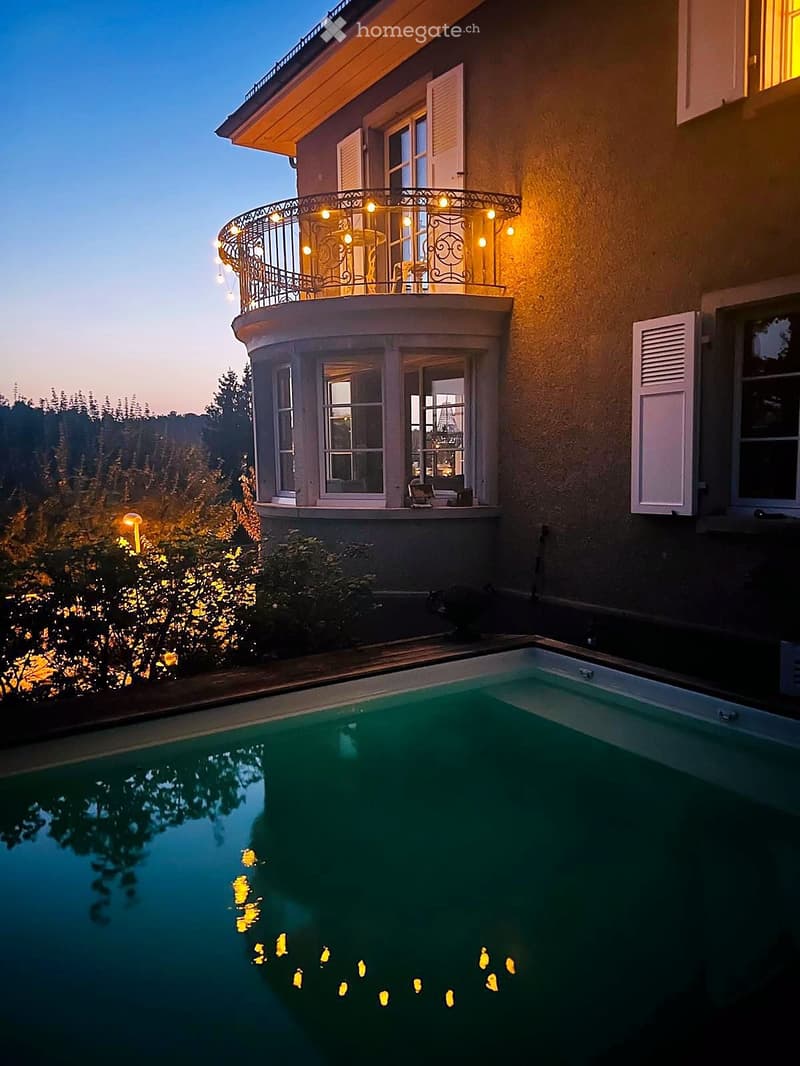 House. Two-story house with a balcony, swimming pool, and outdoor lighting.