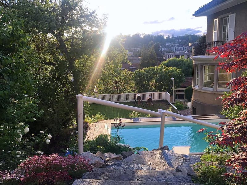 Garden / Outdoor Area. Garden with a swimming pool, surrounded by greenery, flowers, and a view of the city in the background.