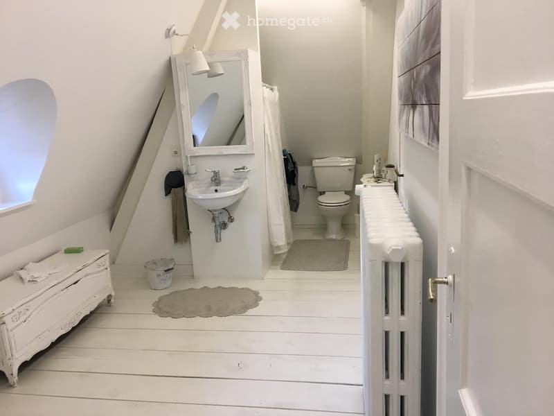 a small bathroom with white tiles, mirror, toilet, sink, and a radiator