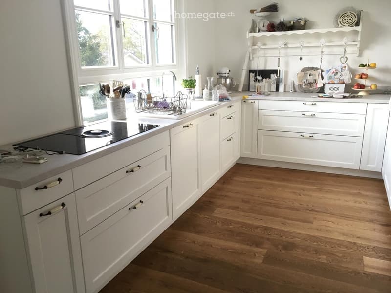 modern kitchen, white cabinetry, wooden floor, island with stovetop, window, modern appliances