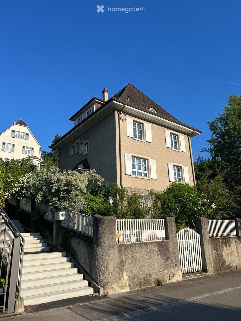 3 story residential house, brown roof, white windows, garden, white fence