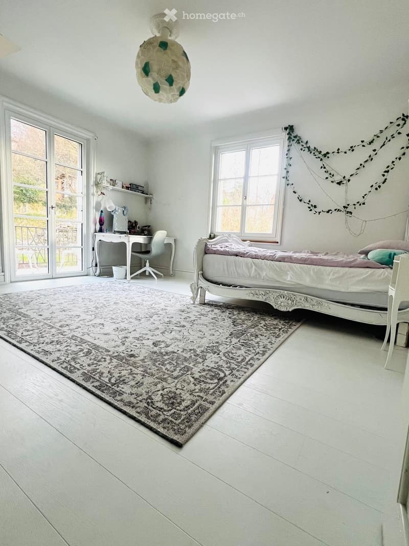 bedroom with bed, desk, chair, and rug; glass doors leading to balcony