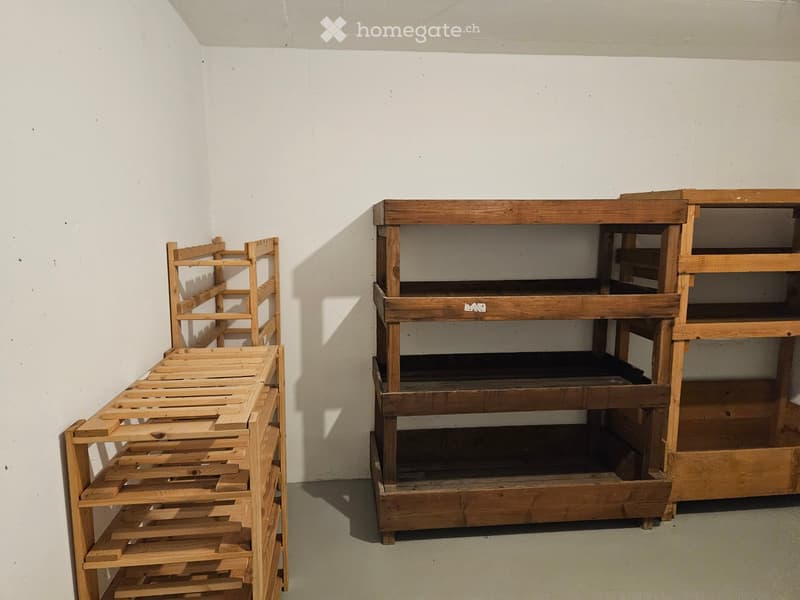 Empty room with white walls and wooden floor, featuring two wooden bed frames stacked against the wall.