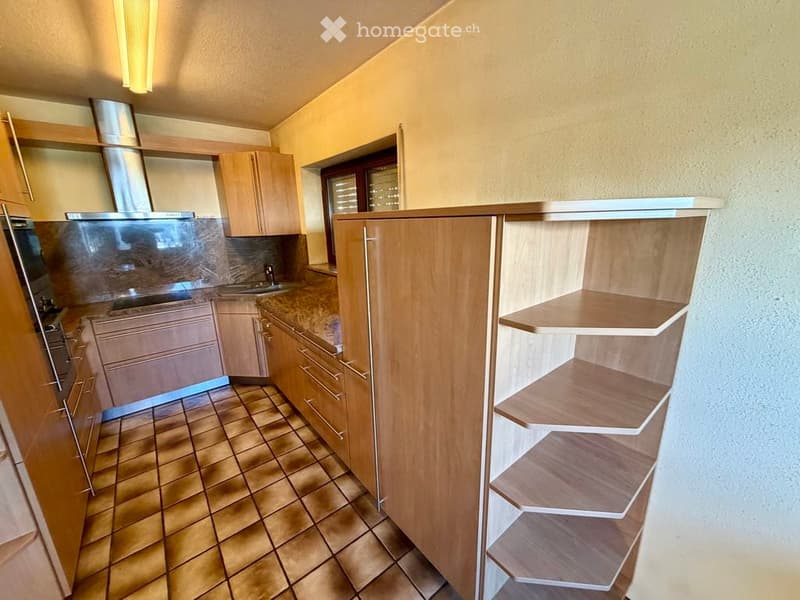Modern kitchen with wooden cabinets, granite countertops, tiled floor, and stainless steel appliances including a sink, oven, and range hood.