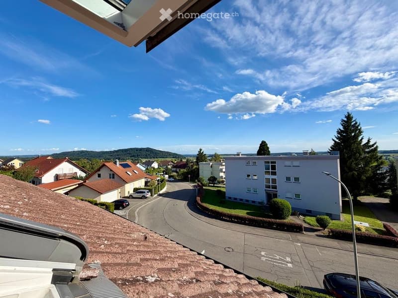 Balcony view overlooking a residential neighborhood with houses, trees, and a clear blue sky.