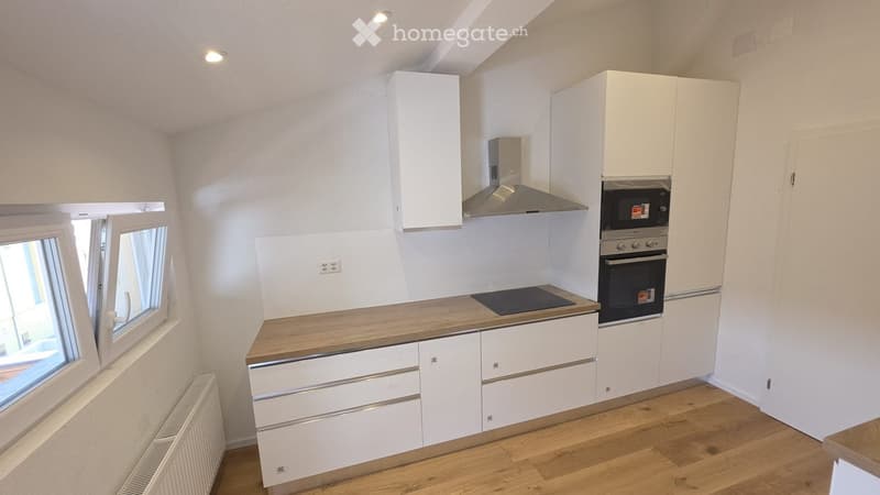 Modern kitchen with white cabinets, wooden countertops, and stainless steel appliances including an oven and range hood.