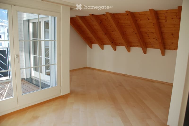 Empty room with wooden flooring, white walls, and large glass doors leading to a balcony.