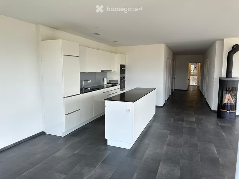 Modern kitchen with white cabinets, dark countertops, and a central island. Features a sink, faucet, and built-in oven.
