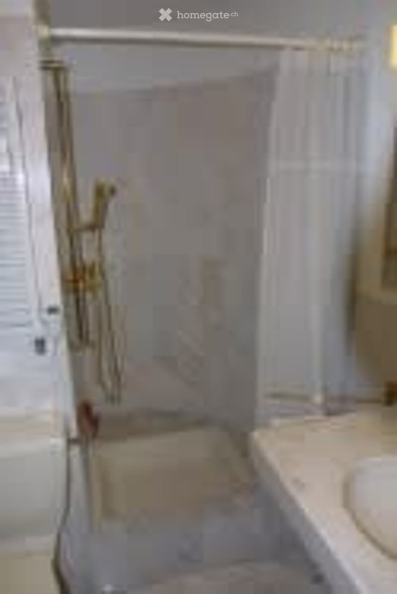 Bathroom with a bathtub, shower, and sink. The shower has a glass enclosure and a gold-colored showerhead.