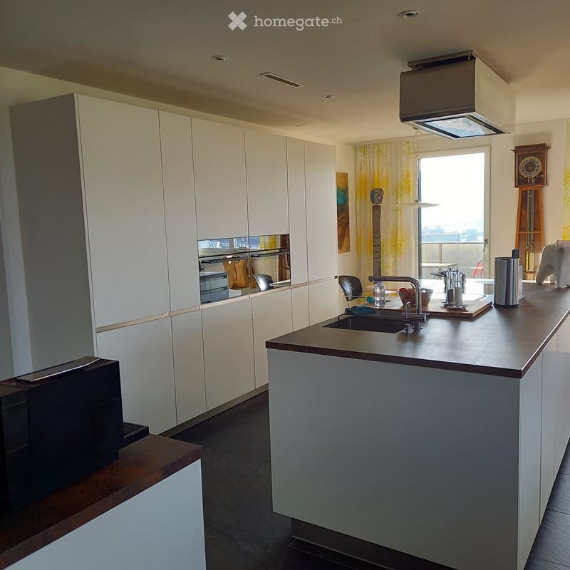 Modern kitchen with white cabinets, dark countertops, and a central island. Features a sink, faucet, and various appliances.