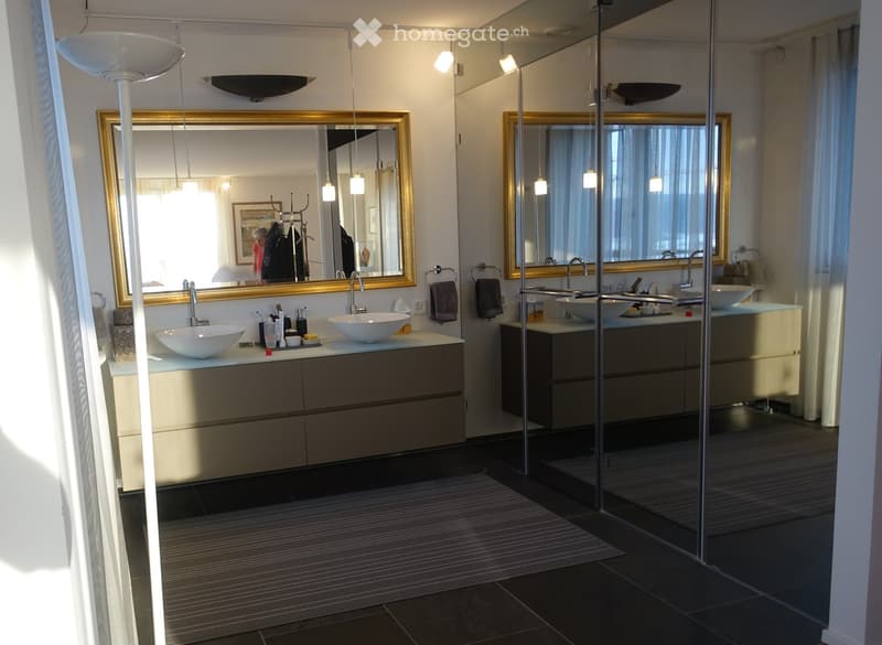Modern bathroom with two sinks, large mirrors, sleek vanities, and contemporary lighting fixtures.