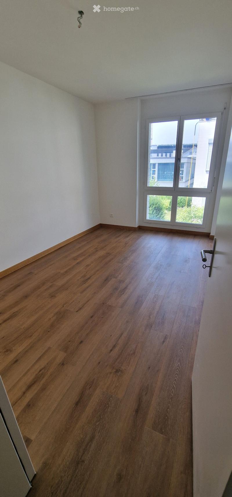 Empty room with wooden flooring and large windows, no furniture or equipment.