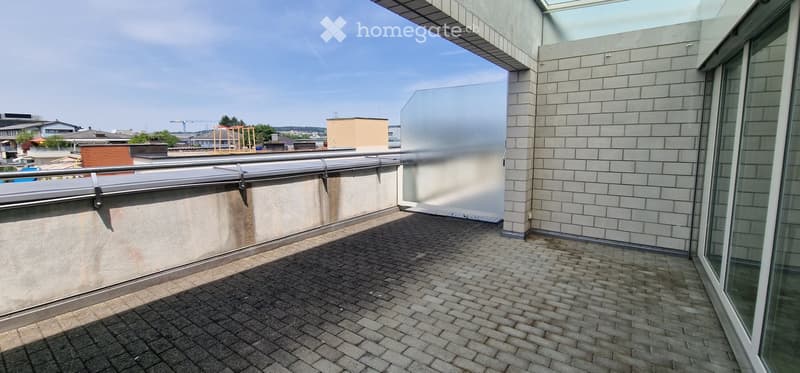 Modern balcony with brick paving, metal railing, and a view of the cityscape and surrounding buildings.