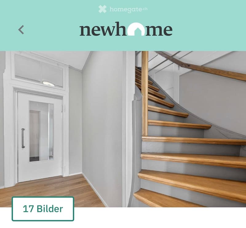 A modern hallway with wooden flooring, a white door with a glass panel, and a wooden staircase leading upwards.