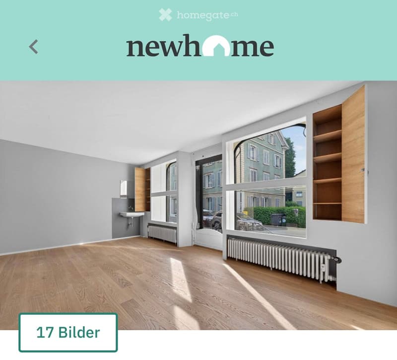Empty room with wooden flooring, large windows, built-in shelving, radiator, and sink area.