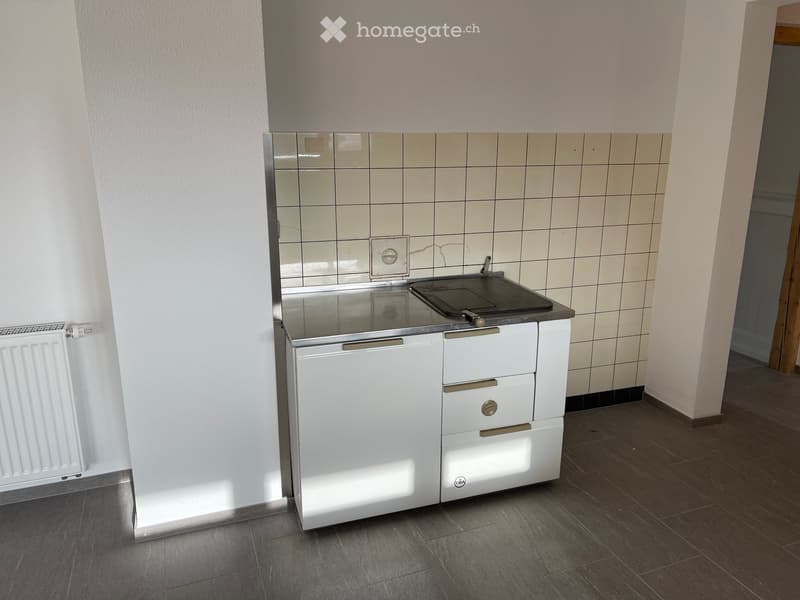 small kitchen area with a sink, countertop, and cabinets
