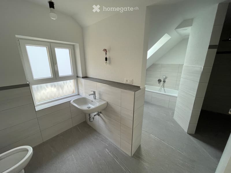 white sink, white toilet, grey tiled floor, white tiles, window, shower
