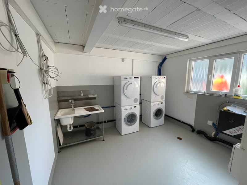 Room with washing machines, sink, and bucket, no other furnishings visible