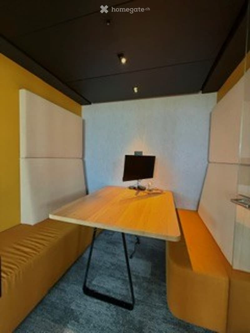 A small, modern workspace with a wooden table, a single chair, and a screen, featuring bright yellow and white walls and a blue carpet.