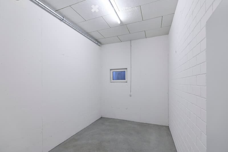 Empty room with white walls, concrete floor, and a single small window. No furniture or equipment present.