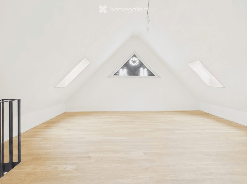 Completely empty room with white walls, wooden floor, and skylight windows.