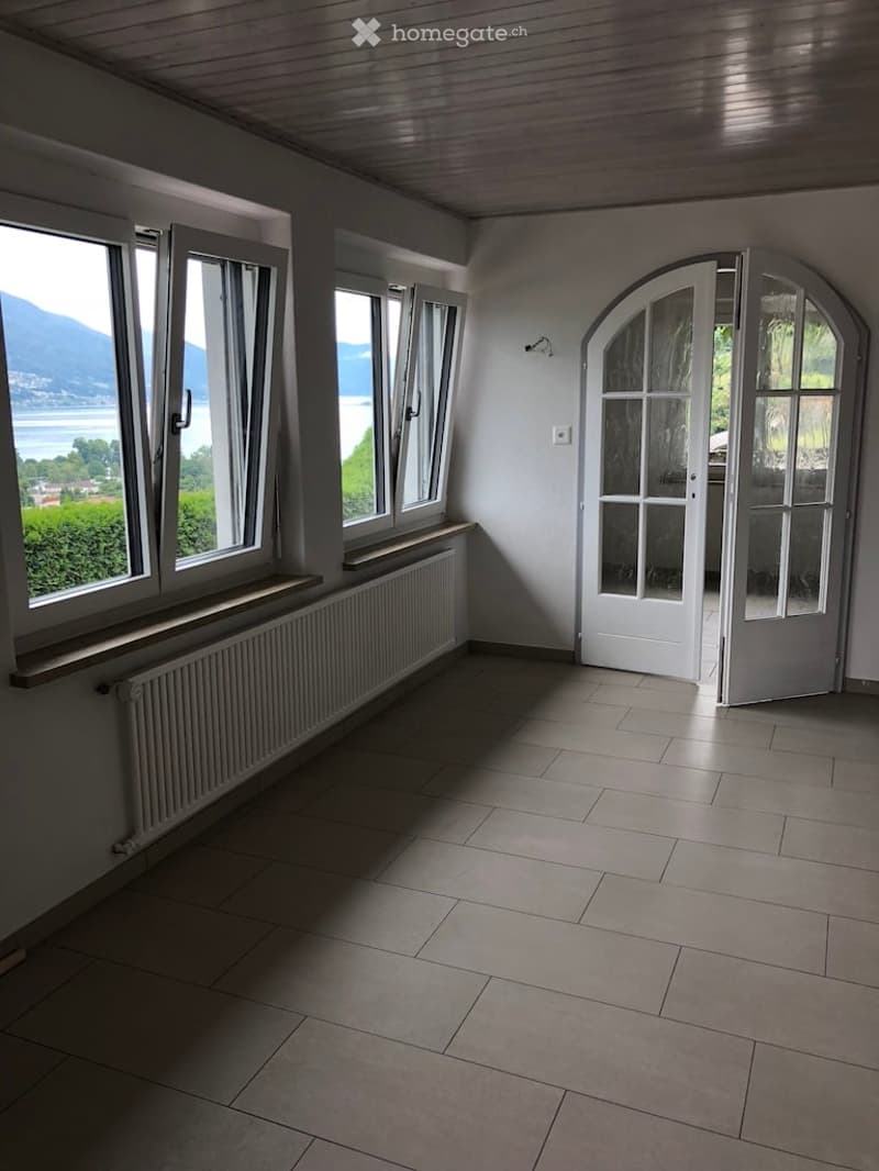 spacious room with windows, white floor, white walls, radiator, open door, view of the sea and mountains