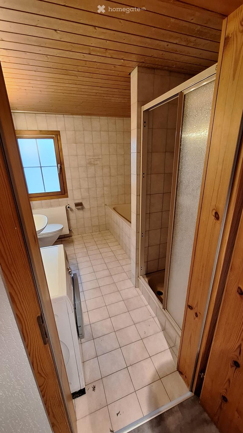 Bathroom with wooden walls and ceiling, tiled floor, bathtub, toilet, sink, and a glass-enclosed shower area.