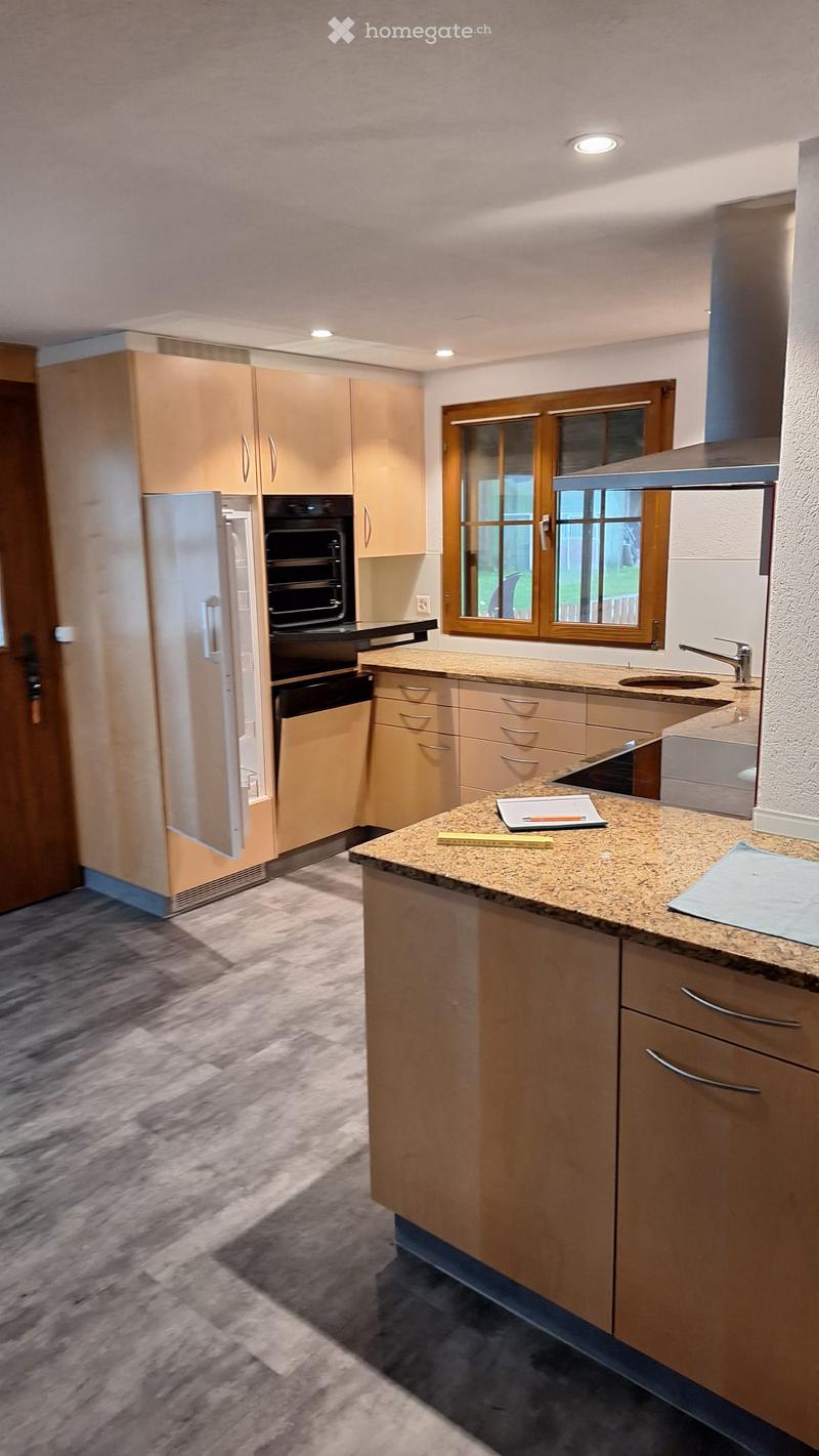 Modern kitchen with light wood cabinets, stainless steel appliances, granite countertop, and a window overlooking the yard.