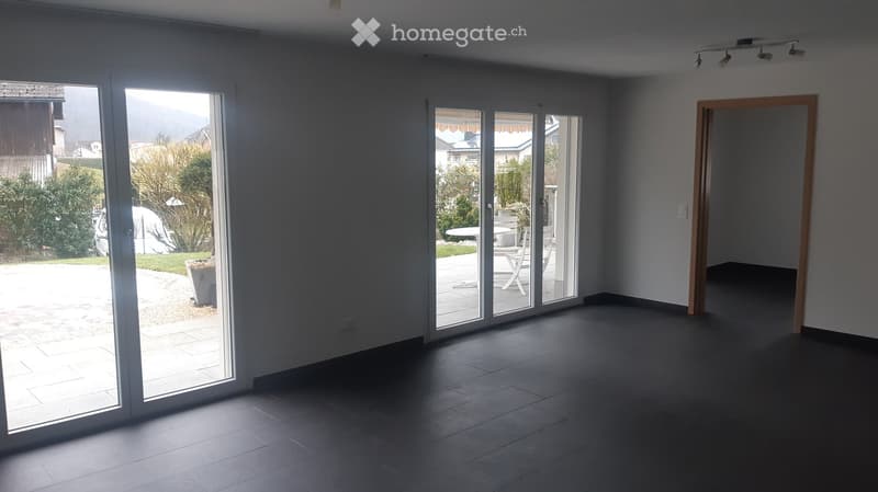 Empty room with large sliding glass doors leading to a patio area, dark tiled floor, and white walls.