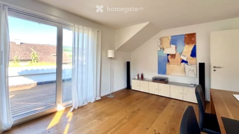 Bright living room with large windows and a balcony, featuring a wooden floor, white walls, a modern cabinet, a floor lamp, and a colorful abstract painting.
