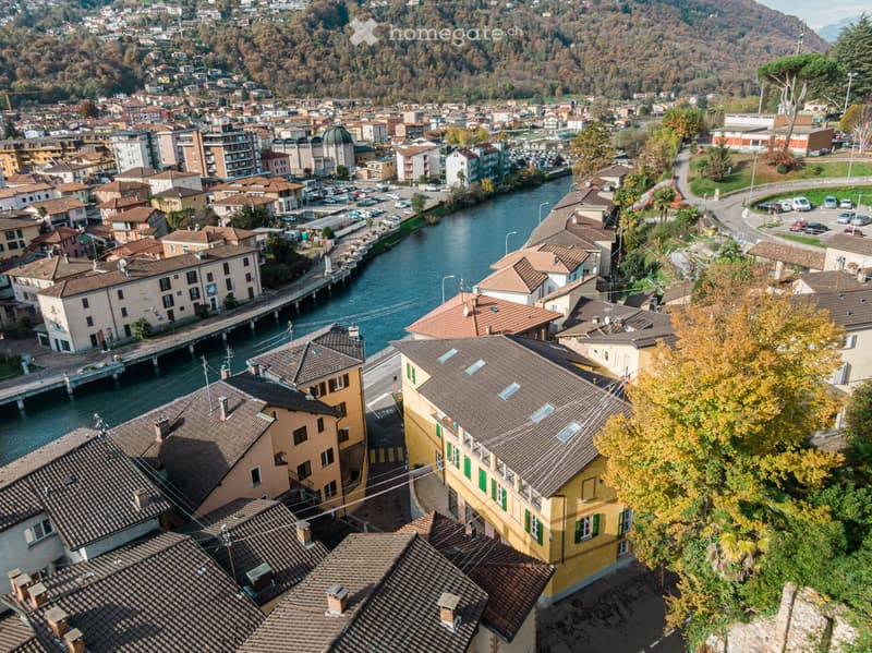 Aerial view of a town with numerous buildings, a river running through, and surrounding hills.