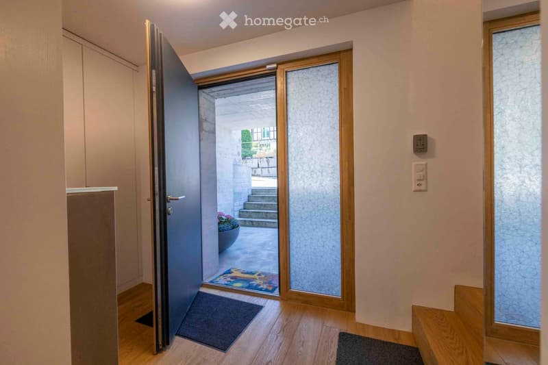 A modern hallway with wooden flooring, a partially open door leading to an outdoor area, and a small bench near the wall.
