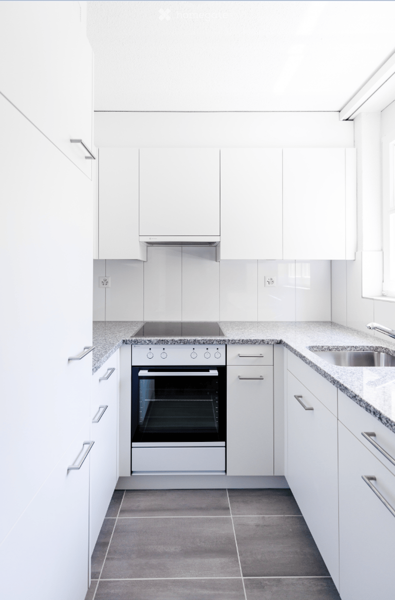 Modern kitchen with white cabinets, stainless steel oven, granite countertops, and a stainless steel sink.