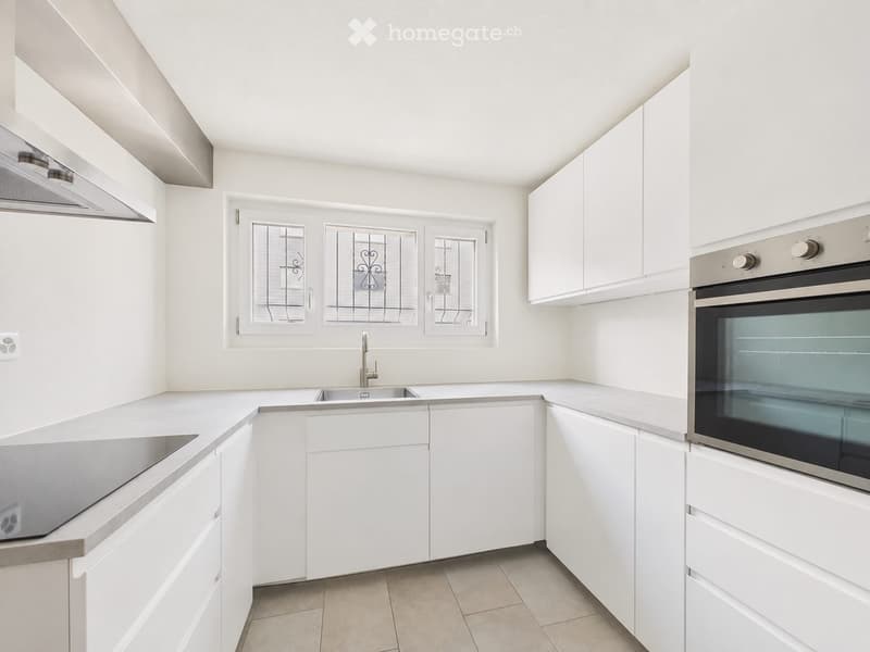 Modern kitchen with white cabinets, stainless steel appliances, and a central island with a sink and faucet.
