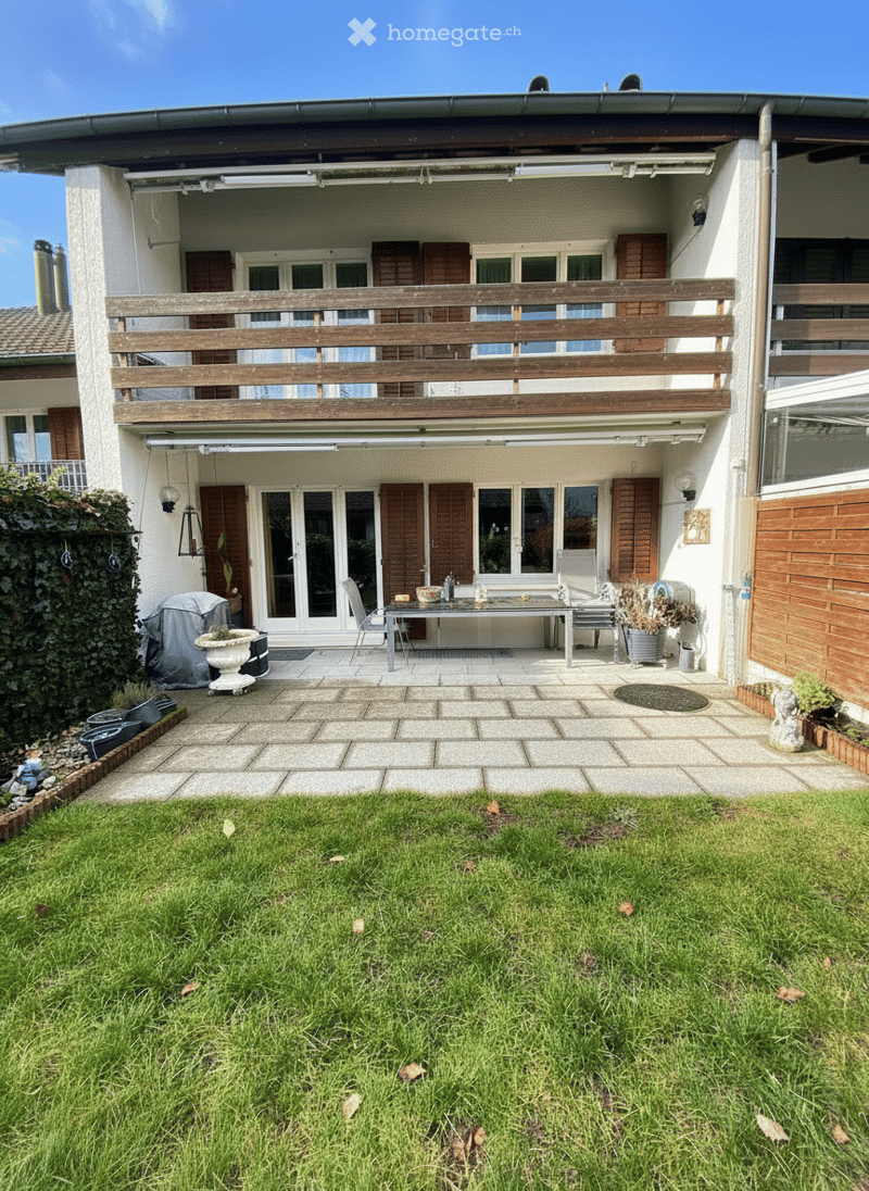 white house, brown shutters, wooden balcony, wooden patio, grassy area, potted plants, table and chairs, green plants