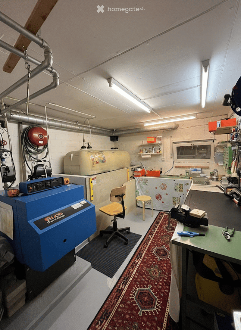 industrial space, large machinery, metal desk, rug, shelves, pipes, lights