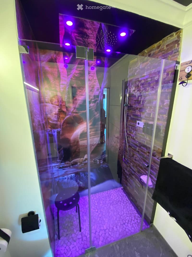 shower cubicle, glass doors, mosaic floor, purple lights, stool, wall with a brick pattern, towel rack