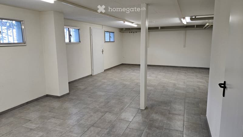 Empty room with tile flooring, white walls, and white doors. There are three small windows and recessed ceiling lighting.