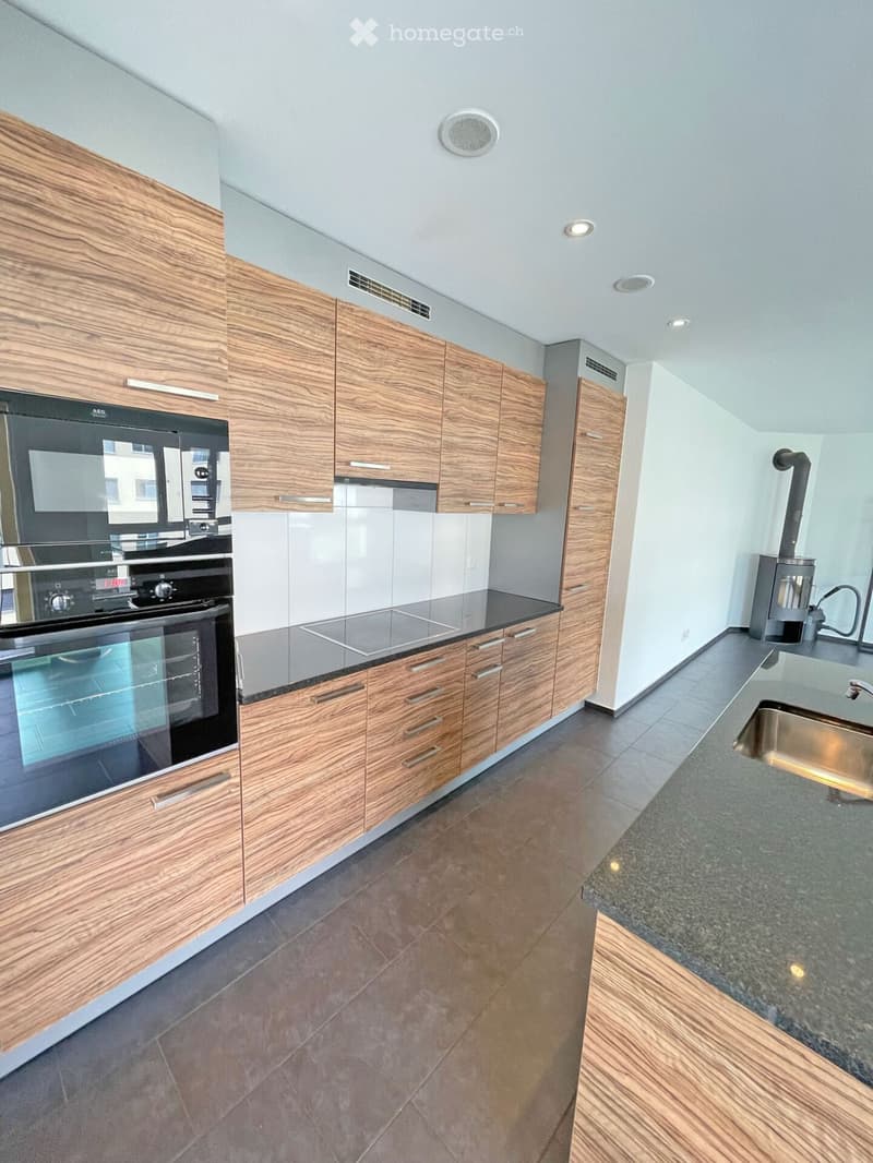Modern kitchen with wooden cabinets, granite countertop, stainless steel sink, and built-in oven.