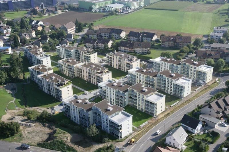 Aerial view of a residential complex with multiple apartment buildings, surrounded by green spaces and roads.