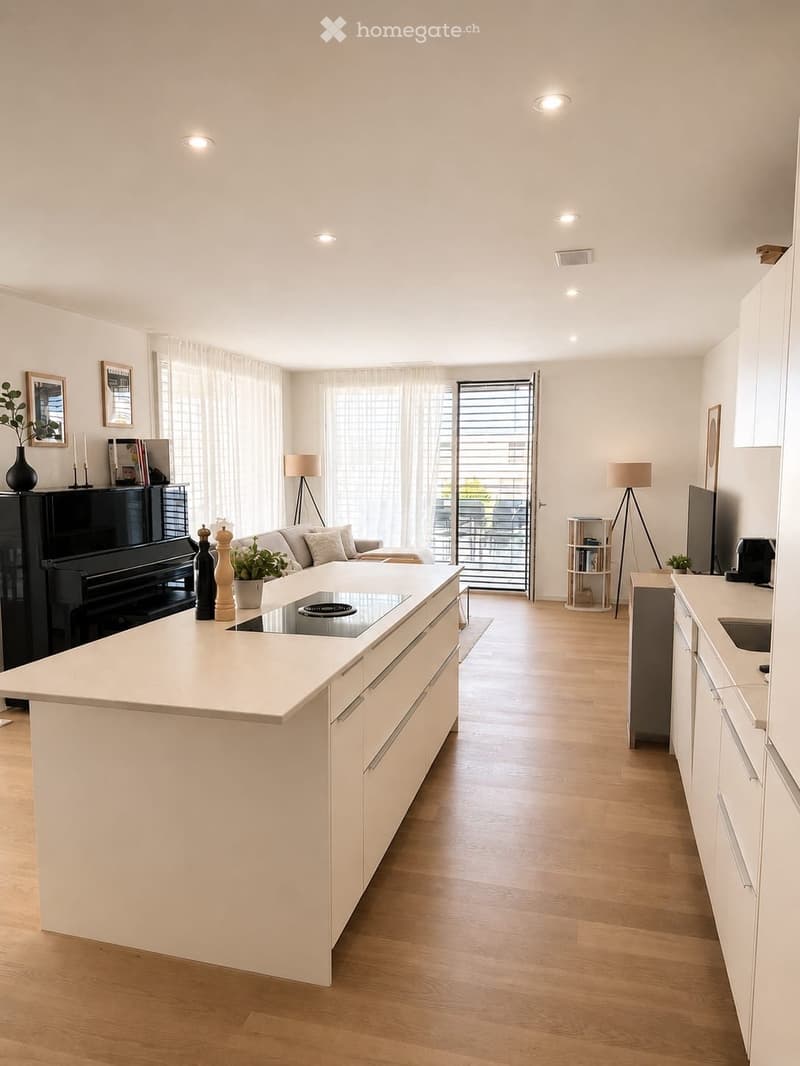 Modern, open-plan living and kitchen area with light wood flooring, white cabinetry, and a central island with an induction cooktop. Features a sofa, coffee table, piano, and large windows with sheer curtains.