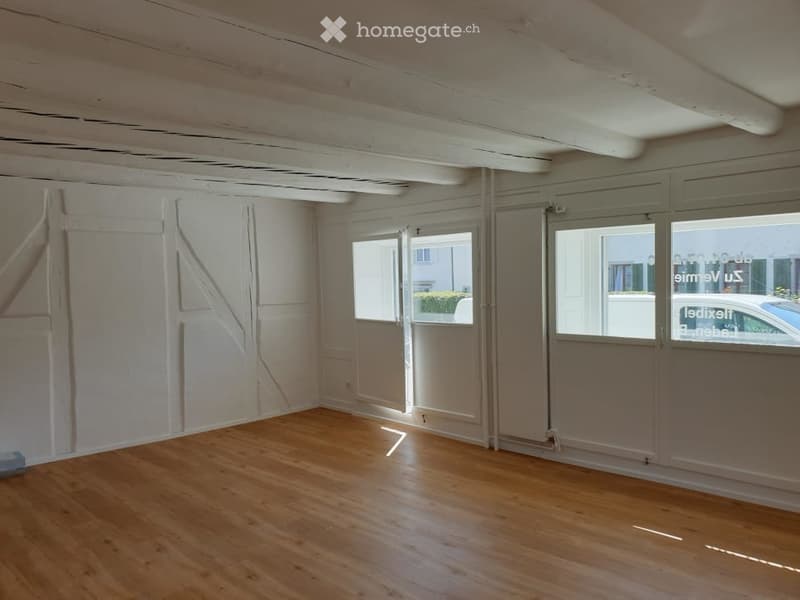Empty room with wooden flooring, white walls, and large windows with blinds. No furniture or equipment present.