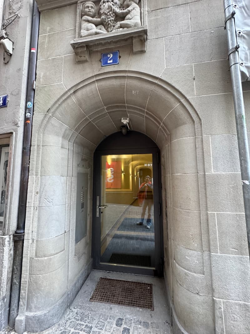 stone building, arched entrance, glass door, number 2 above the entrance, mat in front of the door
