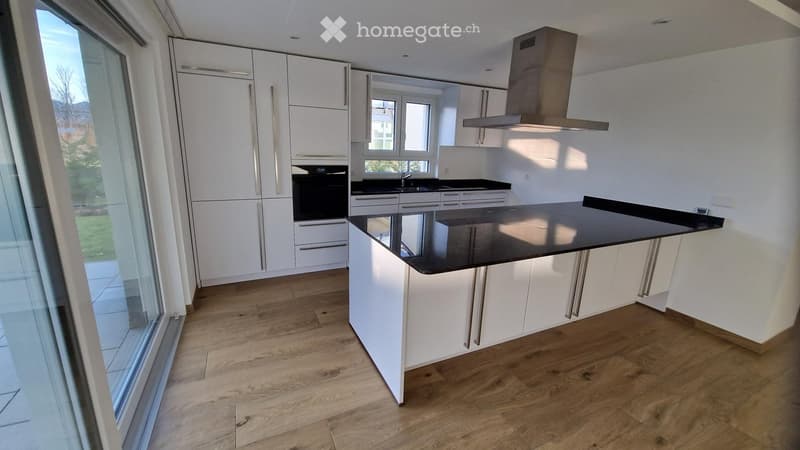 Modern kitchen with white cabinets, a central island, and a black countertop. Features include an oven, range hood, and a sink.