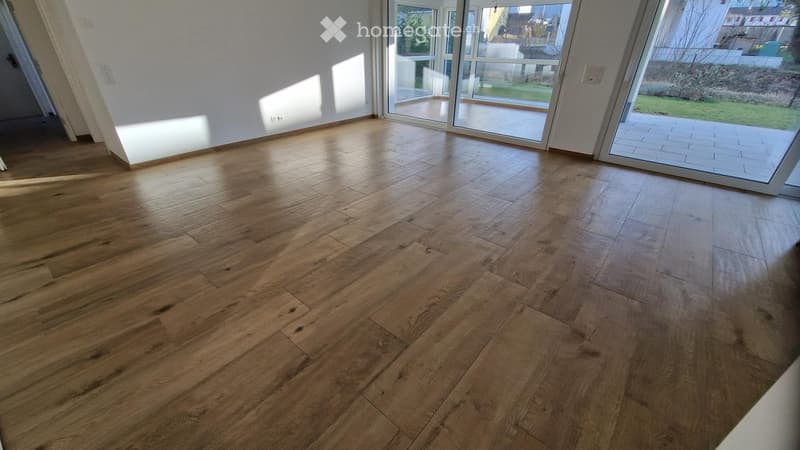 Empty room with wooden flooring and large glass doors leading to an outdoor area.