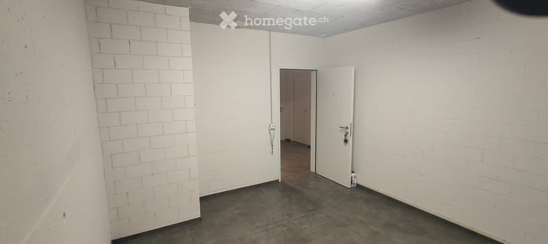 Empty room with white brick walls, concrete floor, and two open doors leading to adjacent spaces.