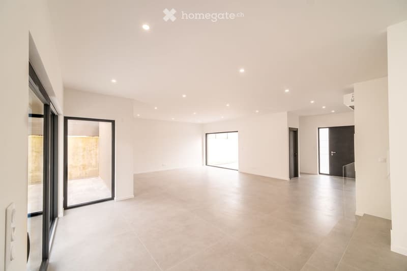 Empty room with white walls, tiled floor, and multiple doors leading to other spaces. No furniture or equipment visible.